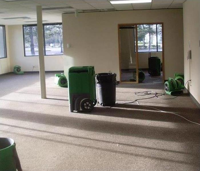 Restoration machines are cleaning water damage in an office
